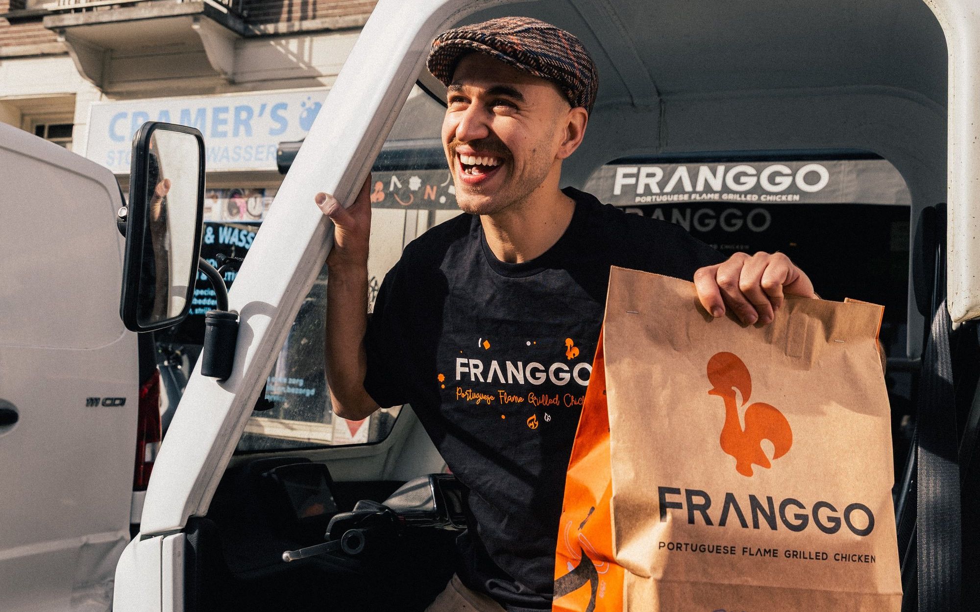 A Franggo driver laughing in the door of the delivery van with a Franggo pickup bag